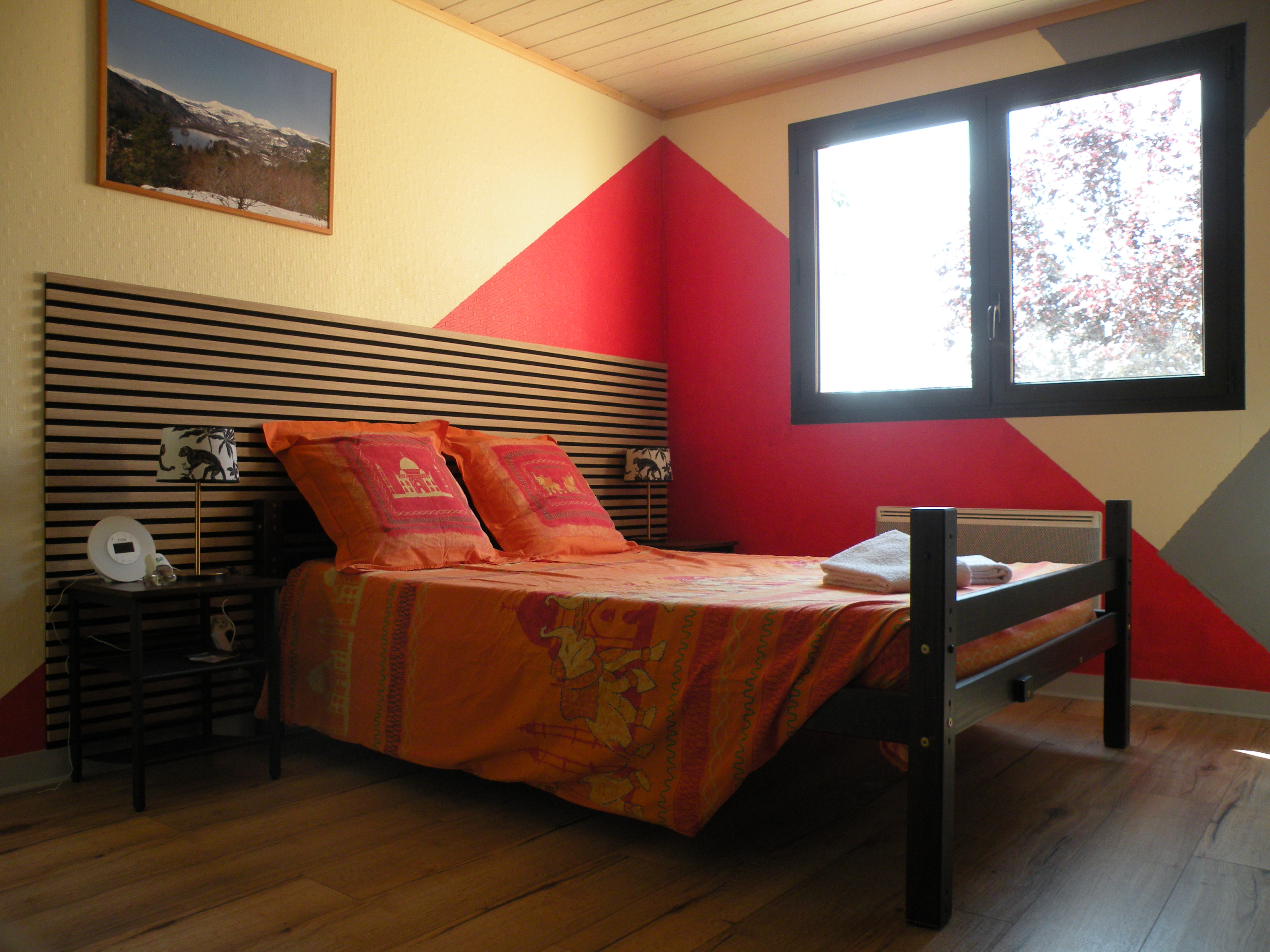 Lit deux places avec tête de lit et drap de couleur orangée